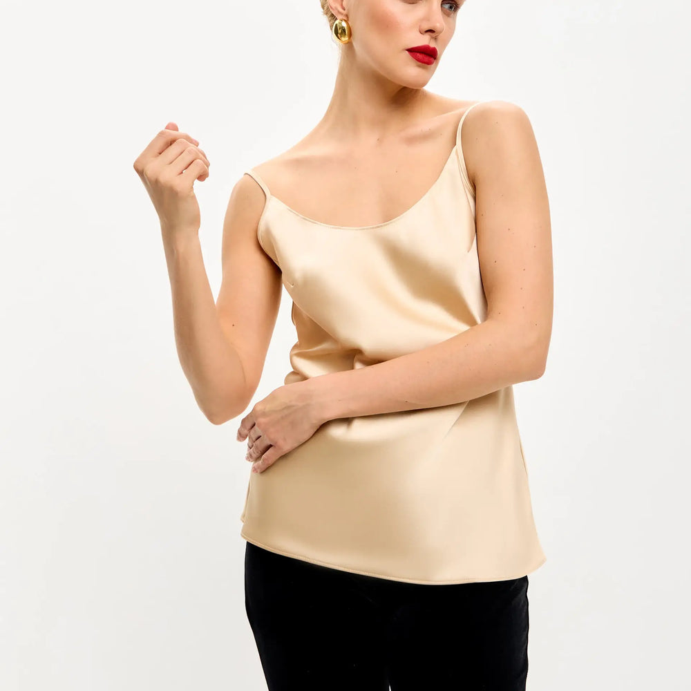 
                  
                    Woman in a beige satin camisole and black pants.
                  
                