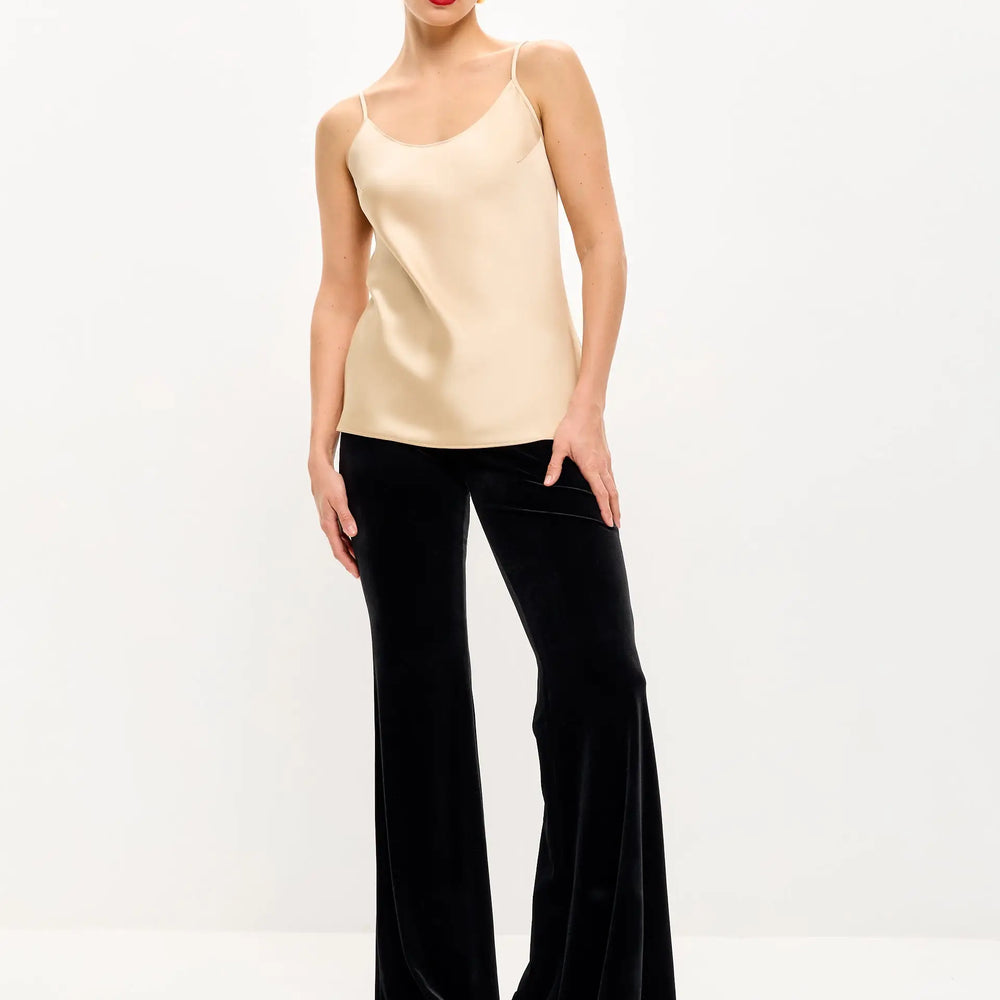 Woman in a beige camisole and black velvet bell-bottom pants.