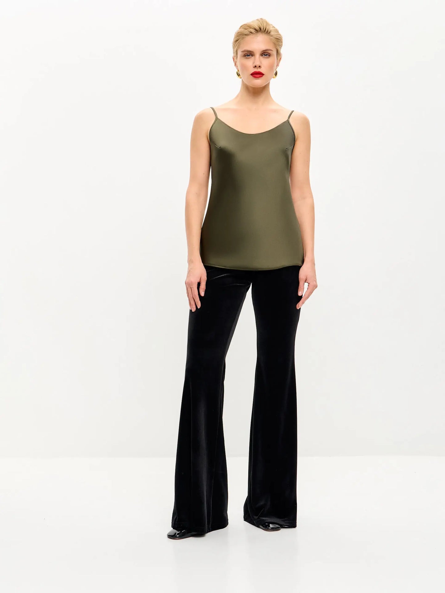Woman in olive green tank top and black velvet bell-bottom pants.